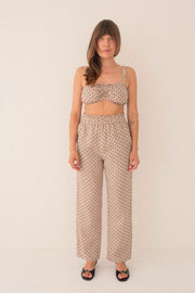 Woman wearing a patterned top and pants on a white background