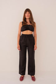 Woman wearing a black outfit with a top and wide-leg pants against a white background