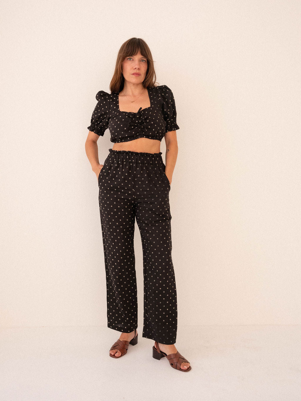 Woman wearing a black polka dot outfit on a white background