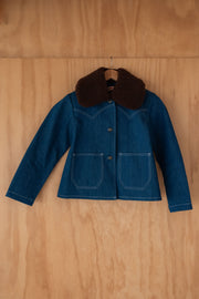 Blue denim jacket with brown fur collar on a wooden surface